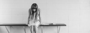 Women sitting on bench looking down sad.