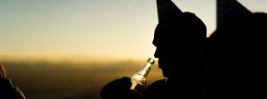 Man looking into a beer bottle outside.