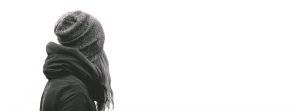 Black & white image of upper half of female looking away with a beanie on.