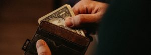 Man grabbing a 1 dollar bill from his wallet.