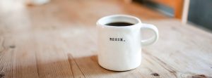 Full white coffee cup with the word "Begin" on it.