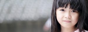 Little girl's face looking forward with bangs and black hair.
