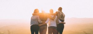 Four friends linked arms looking out at a nature view.