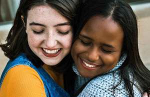 woman in yellow shirt hugging woman in blue shirt