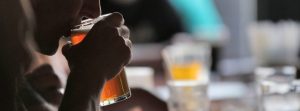 close up of woman sipping beer at a bar.