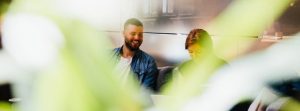 Man and woman laughing at laptop in a public place.
