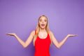 Happy woman in a red tank top with her arms out to her sides in front of a purple background.