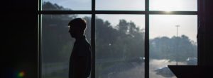 Shadowed man standing in front of a window.