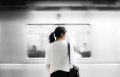 woman in white shirt standing in front of subway.
