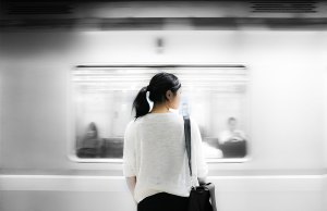 woman in white shirt standing in front of subway.