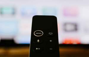 Black remote in front of tv screen.
