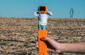 person wearing orange TV helmet with remote in field