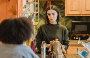 two young women talking in the interior of a kitchen