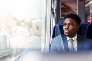 Business man in a blue suit looking out a window on a train