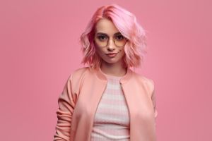 Confident woman with pink hair and jacket facing forward.