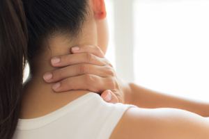 Woman touching her neck like she's in pain.