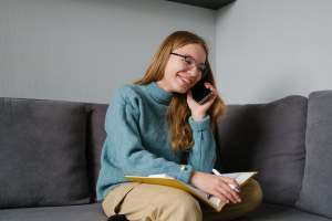 Woman on the couch talking on the phone and taking notes