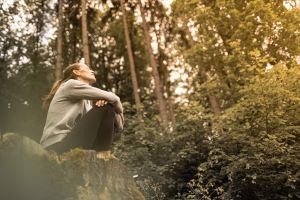 Woman breathing deeply on a rock in the forest